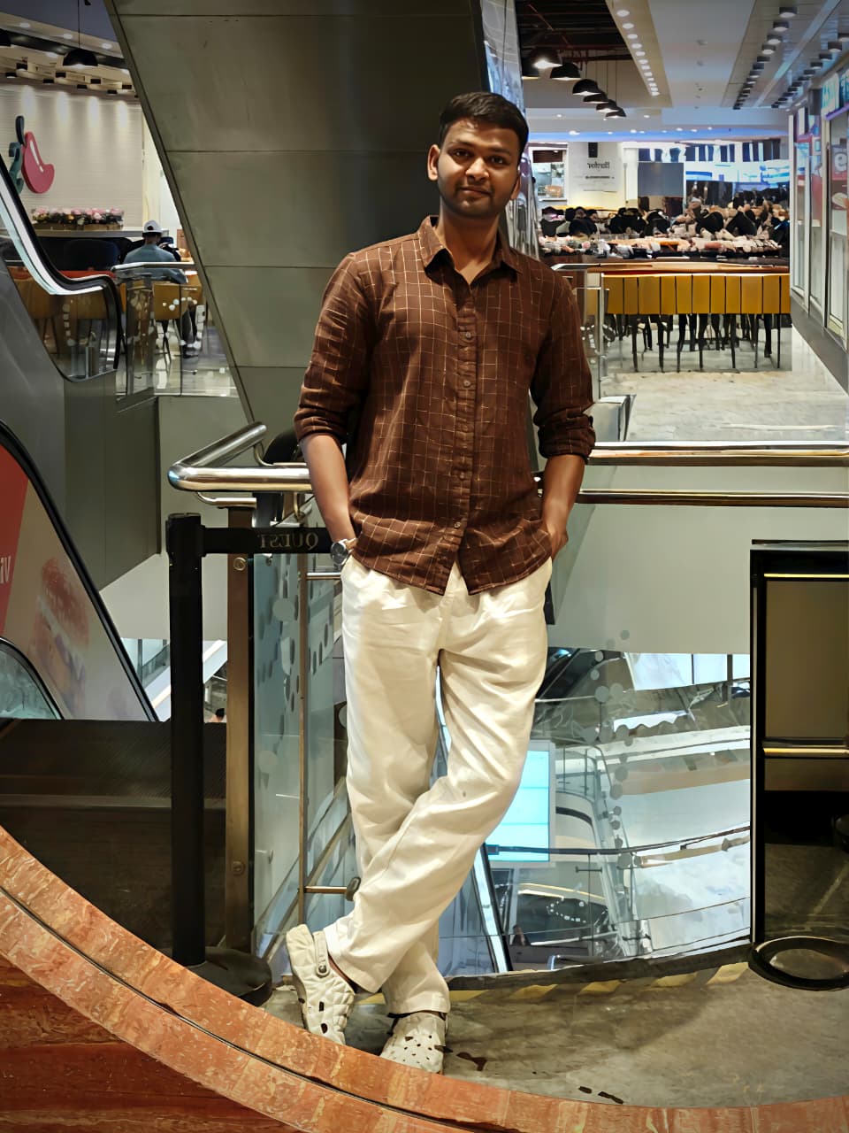 amanullah in a mall standing and posing in a white trouser and brown shirt